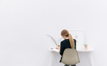 Eine junge Frau sitzt an ihrem Schreibtisch und arbeitet.