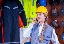 Arbeitskleidung Rechte und Pflichten für Betriebe und Mitarbeiter Frau beim Telefonieren mit Sicherheitshelm.