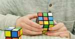 Ein junger Mann löst einen Rubik's Cube.