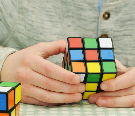 Ein junger Mann löst einen Rubik's Cube.